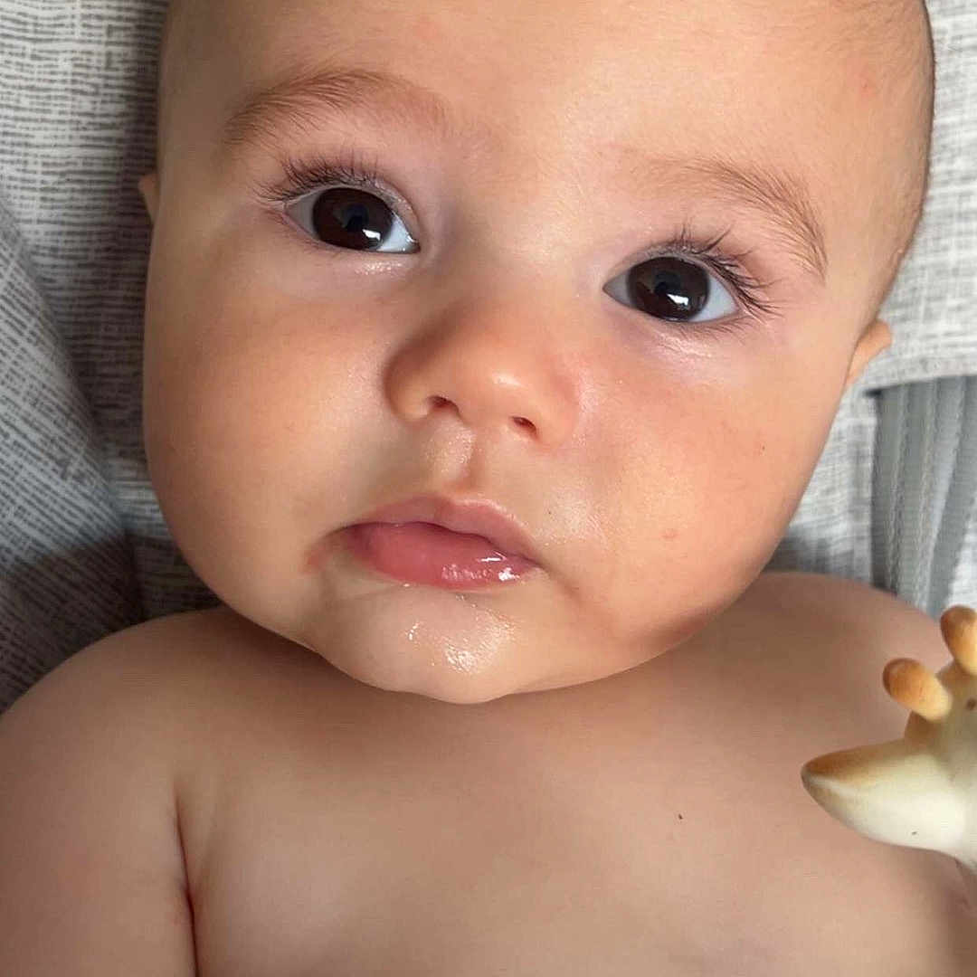 Liam a rejoint le concours — aidez-le/la à gagner de superbes lots ! baby, bare_chest, cheeks, child, closeup, curious, eyes, fabric, face, giraffe, hand, infant, lips, lying_down, mouth, pattern, portrait, skin, teething_toy, toy