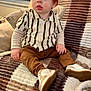 Santino is registered to the contest to win money with this photo: child, toddler, red_hair, blue_eyes, striped_shirt, knit_shirt, pants, sneakers, blanket, couch, pillows, indoor, portrait, seated, looking_up, cozy, home, lamp, window_blinds, cute