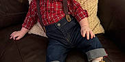Santino is registered to the contest to win money with this photo: baby, boots, casual_clothing, child, comfortable, couch, cozy, cute, footwear, happy, indoor, jeans, pillow, plaid_shirt, portrait, red_hair, rolled_jeans, seated, smiling, suspenders