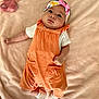 baby, infant, headband, orange_overalls, white_shirt, white_socks, blanket, plush_toy, butterfly_toy, soft_texture, lying_down, cute, portrait, child, indoors, cozy, comfortable, small_hands, curious_look, pink