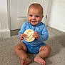 Rowen joined the competition — help win amazing prizes! baby, child, smiling, blue_clothing, sitting, carpet, indoor, holding_object, wooden_sign, seven_months, face, feet, hands, door, wall, home, infant, cute, portrait, person