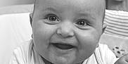 Rowen is registered to the contest to win money with this photo: baby, smiling, infant, face, portrait, closeup, black_and_white, happy, cute, child, person, clothing, couch, hand, indoors, young, expression, sitting, skin, head