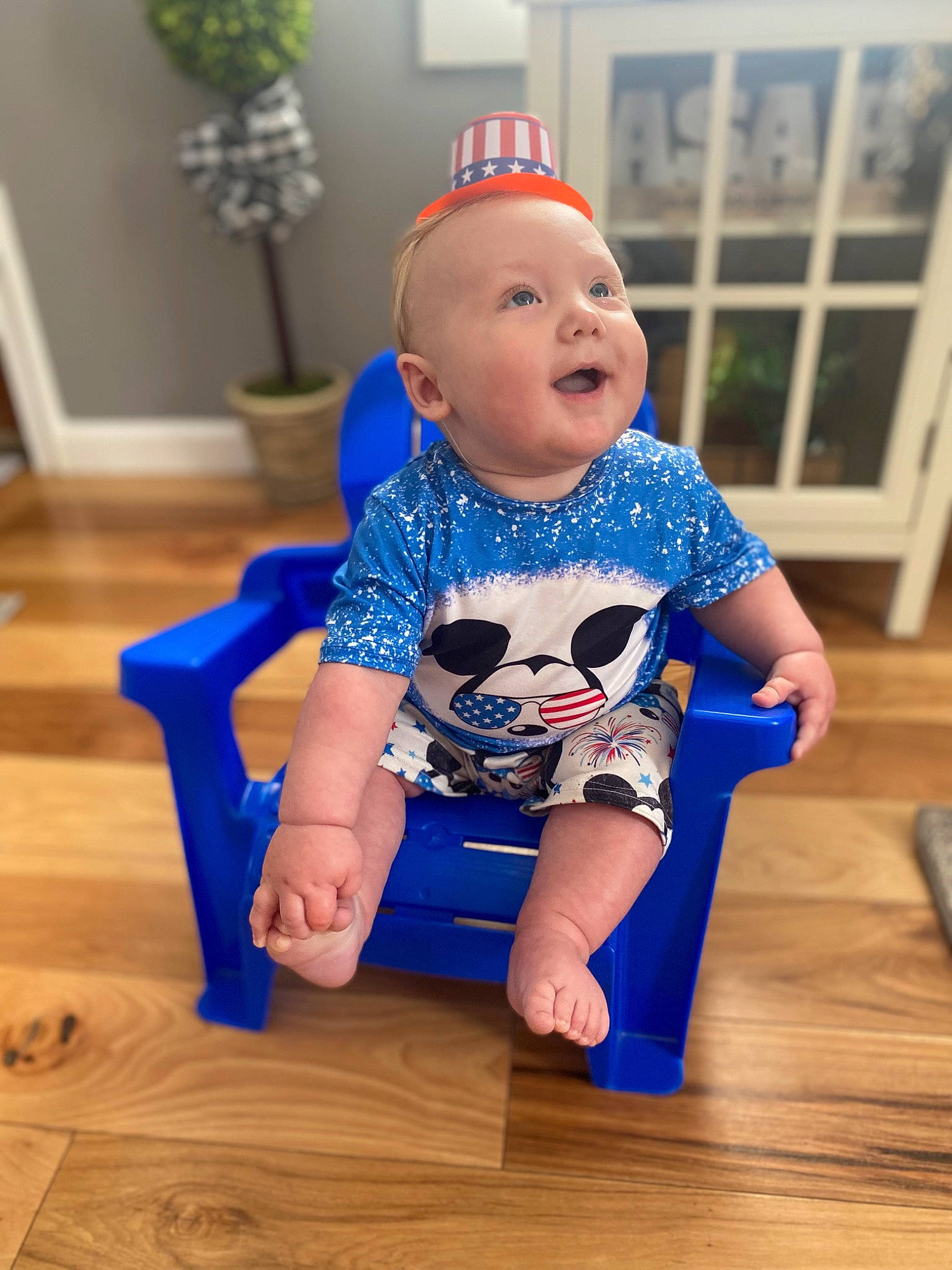 Liam is registered to the contest to win money with this photo: azure, baby, baby_toddler_clothing, cap, electric_blue, floor, flooring, flowerpot, fun, happy, hardwood, hat, houseplant, knee, person, skin, sleeve, smile, t_shirt, toddler
