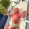 baby, bassinet, bed, cap, child, clinic, diaper, healthcare, hospital, infant, lying_down, medical, newborn, nursery, patient, person, pink_skin, striped_linen, umbilical_clamp, wristband