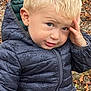 autumn, blonde_hair, blue_eyes, casual_clothing, child, fall, hand_on_head, jacket, leaves, nature, outdoor, person, playful_expression, portrait, puffy_jacket, toddler, toy_car, tree_trunk, yellow_toy, young_child