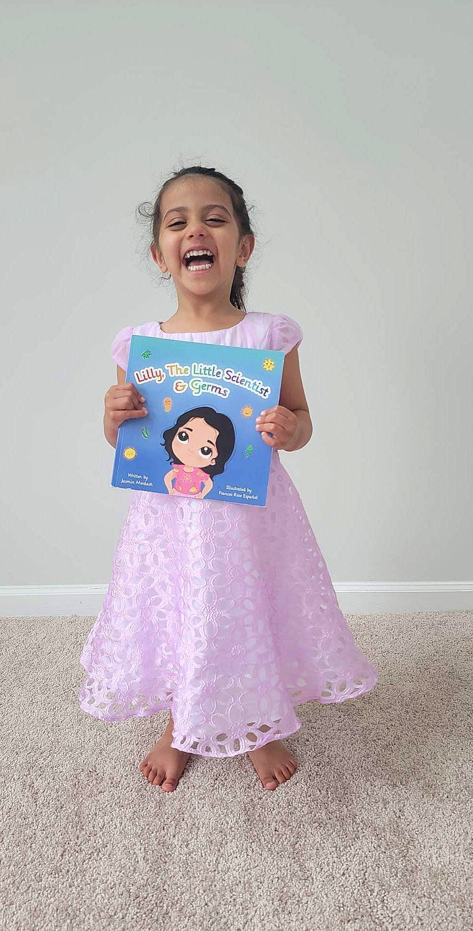 Lilly is registered to the contest to win money with this photo: arm, baby_toddler_clothing, day_dress, dress, facial_expression, fashion_design, fun, gesture, hair, hairstyle, happy, joy, neck, one_piece_garment, outerwear, person, pink, shoulder, sleeve, smile