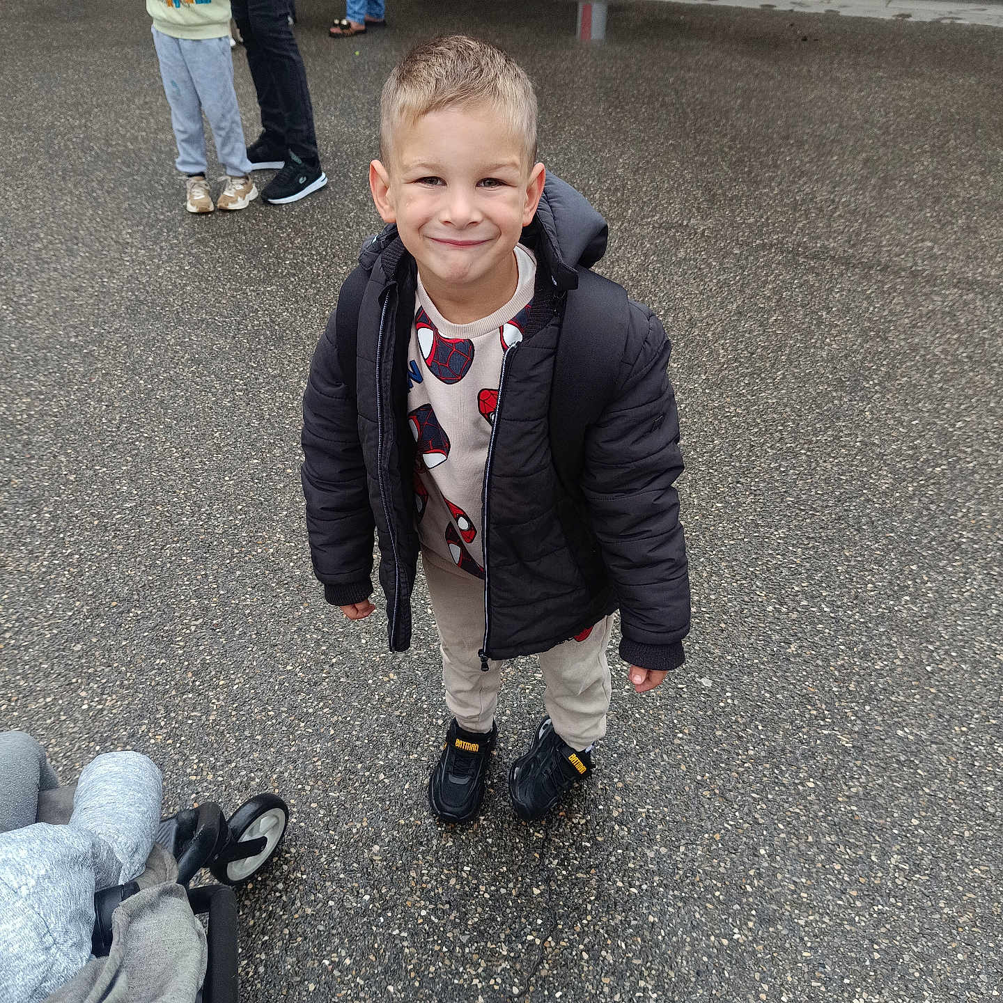 Gennaro participe au concours pour gagner de l'argent avec cette photo : child, boy, smile, jacket, sweater, spiderman, shoes, pavement, stroller, people, outdoor, casual, standing, wet_ground, hoodie, backpack, happy, playful, urban, daytime