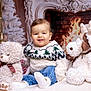 baby, child, stuffed_animal, teddy_bear, reindeer, fireplace, christmas_tree, holiday, cozy, sweater, jeans, smiling, indoor, decorations, plush, festive, cute, portrait, winter, warmth