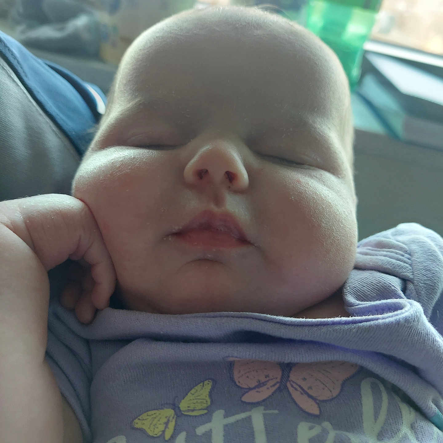 Sofia is registered to the contest to win money with this photo: apparel, baby, butterfly, child, chubby_cheeks, closeup, cute, face, hand, indoors, infant, peaceful, person, portrait, purple_shirt, relaxed, resting, sleeping, soft_light, young