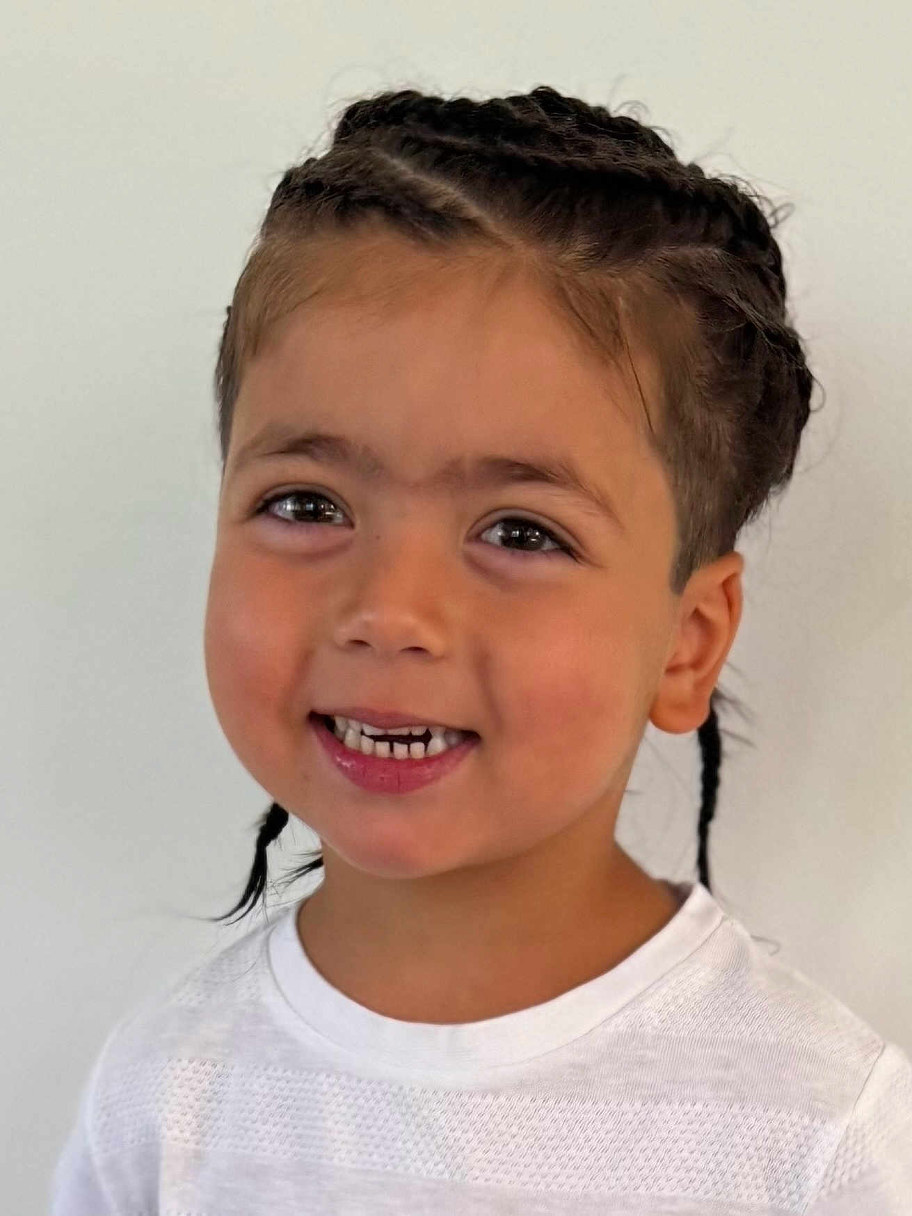Nayel participe au concours pour gagner de l'argent avec cette photo : child, smiling, braids, hair, white_shirt, portrait, face, happy, young, cute, childhood, skin, person, indoors, casual, fashion, headshot, expression, human, background