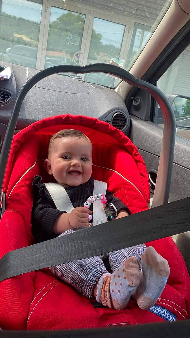 Luna a rejoint le concours — aidez-le/la à gagner de superbes lots ! auto_part, automotive_design, automotive_exterior, baby, baby_carriage, baby_toddler_clothing, car_seat, comfort, joy, leisure, motor_vehicle, person, plant, product, red, smile, steering_part, steering_wheel, toddler, travel
