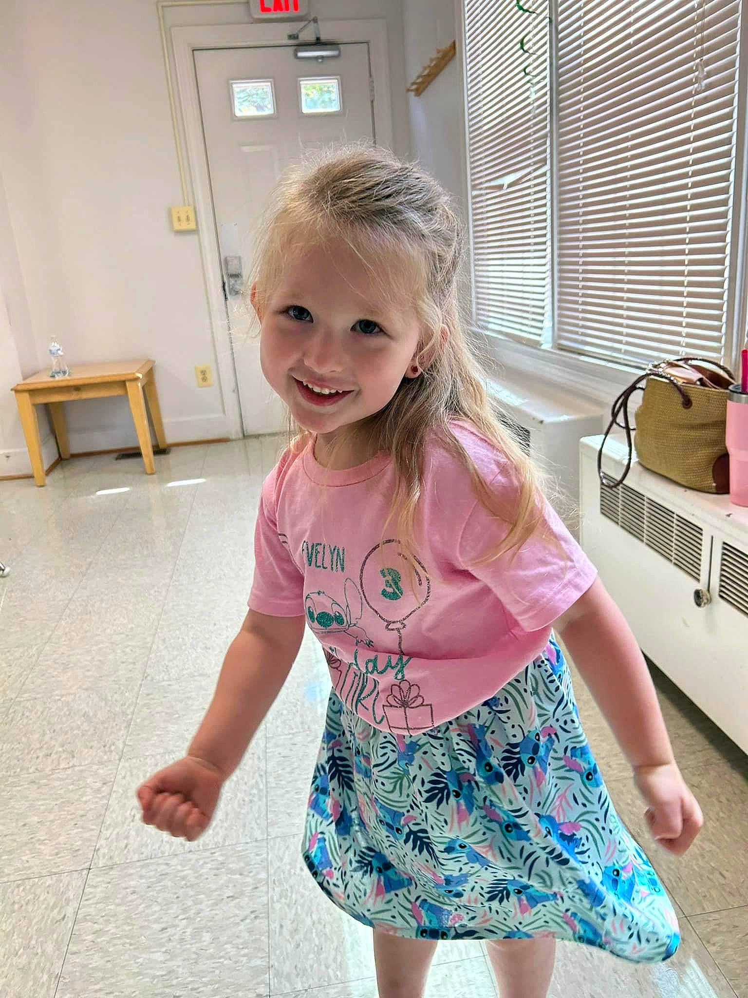 Evelyn is registered to the contest to win money with this photo: baby_toddler_clothing, blond, child, day_dress, dress, flooring, fun, hand, happy, iris, joint, joy, magenta, pattern, person, sleeve, smile, standing, t_shirt, toddler