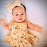 baby, infant, child, portrait, lying_down, bed, white_bedding, headband, bow, dress, overalls, winnie_the_pooh, patterned_clothing, wide_eyes, face, indoors, soft_lighting, cute, fashion, photography