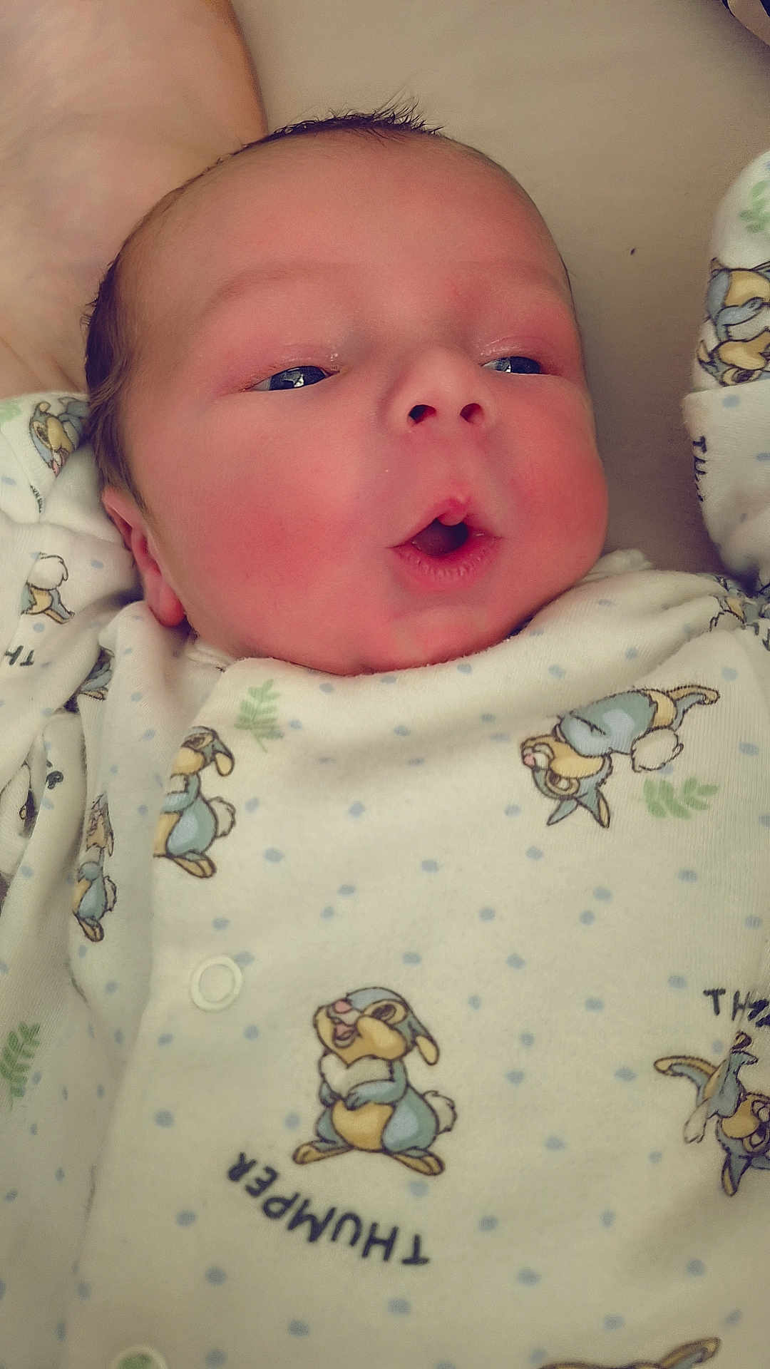 Thomas joined the competition — help win amazing prizes! baby, newborn, infant, face, expression, onesie, clothing, cartoon, animal_print, cute, soft_lighting, closeup, skin, head, small_hands, lying_down, indoors, sleepwear, adorable, child