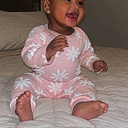 Alani joined the competition — help win amazing prizes! baby, child, smiling, pink_clothing, flower_pattern, sitting, bed, quilt, happy, infant, cute, indoors, person, toes, hands, earrings, face, portrait, cozy, home