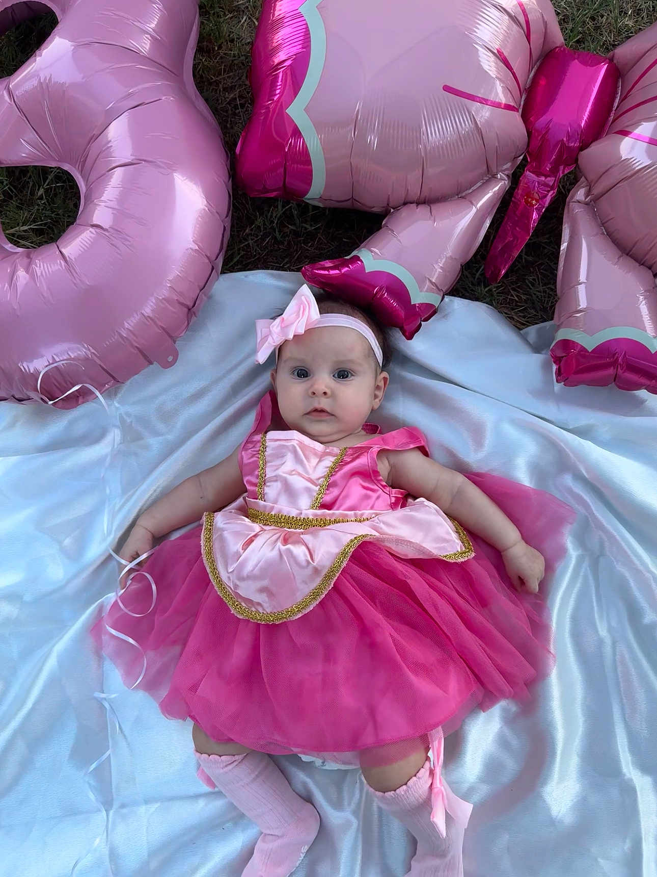 Virginia Danery is registered to the contest to win money with this photo: baby, infant, pink_dress, tutu, headband, balloons, outdoor, grass, blanket, socks, cute, portrait, child, celebration, party, face, lying_down, adorable, person, festive