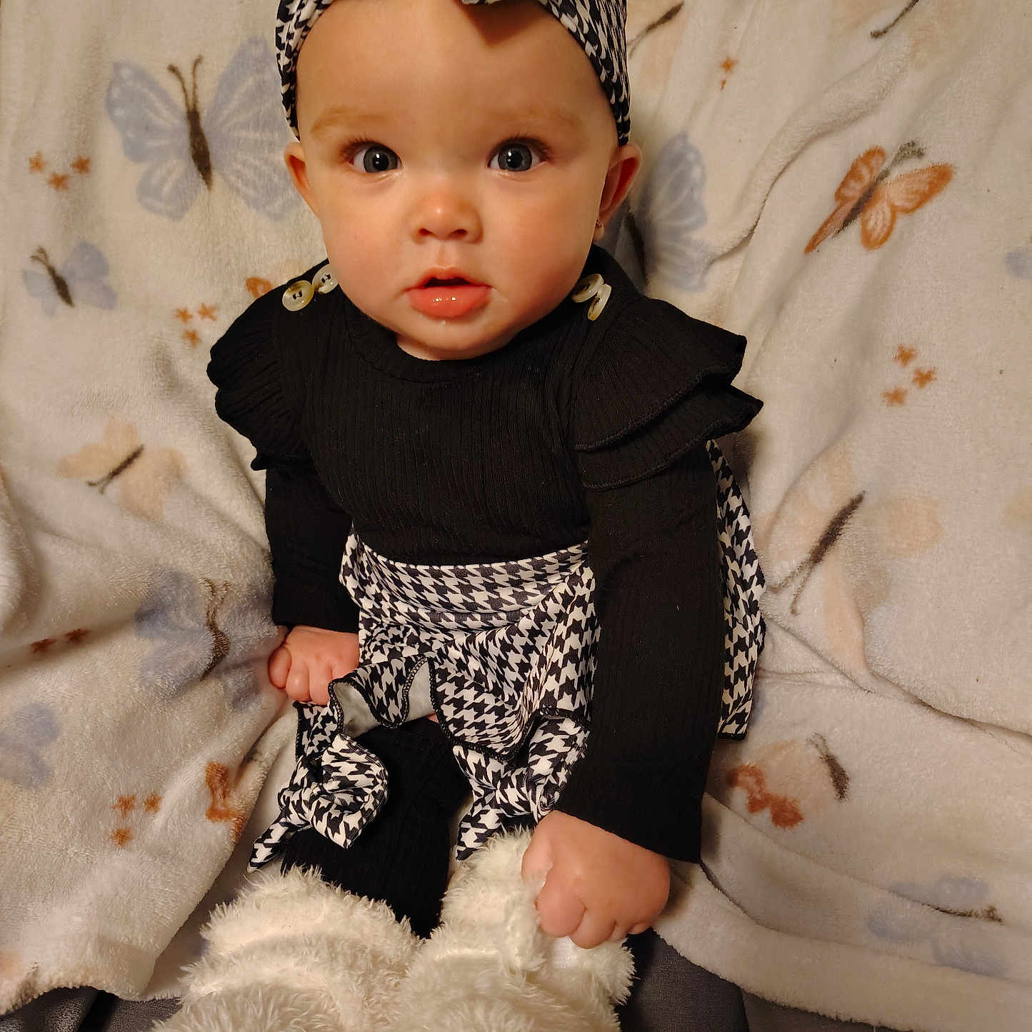 Maci is registered to the contest to win money with this photo: baby, black_clothing, blanket, boots, butterfly_pattern, child, cozy, curious, cute, fashion, fur_boots, headband, houndstooth_pattern, indoors, infant, portrait, sitting, soft_texture, warm, wide_eyes