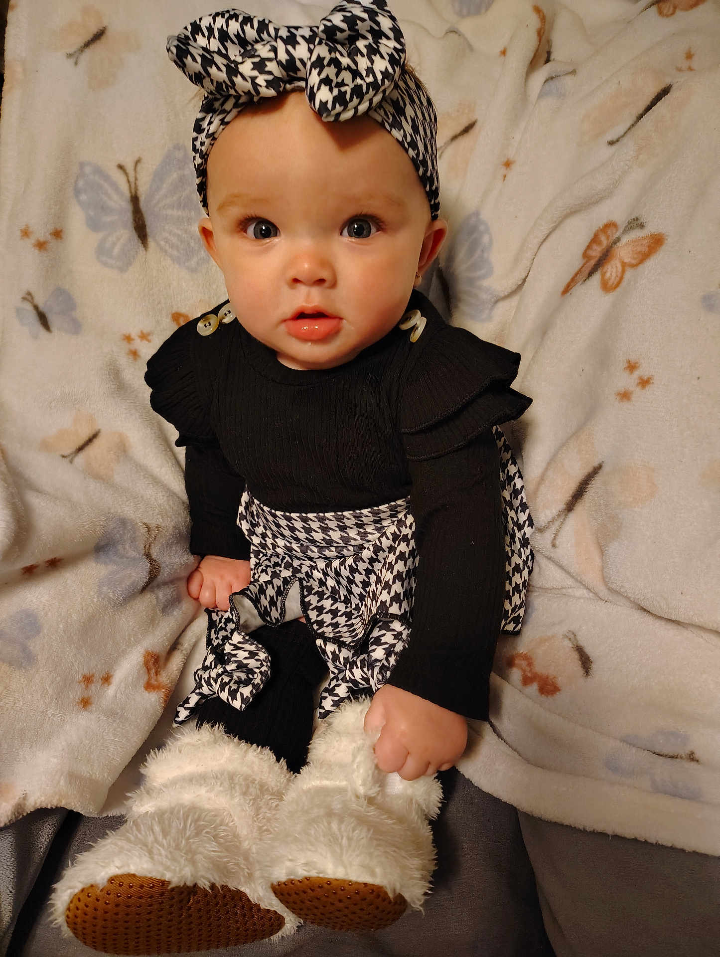 Maci is registered to the contest to win money with this photo: baby, child, infant, black_clothing, houndstooth_pattern, headband, blanket, butterfly_pattern, boots, fur_boots, cute, portrait, sitting, indoors, cozy, wide_eyes, curious, fashion, soft_texture, warm