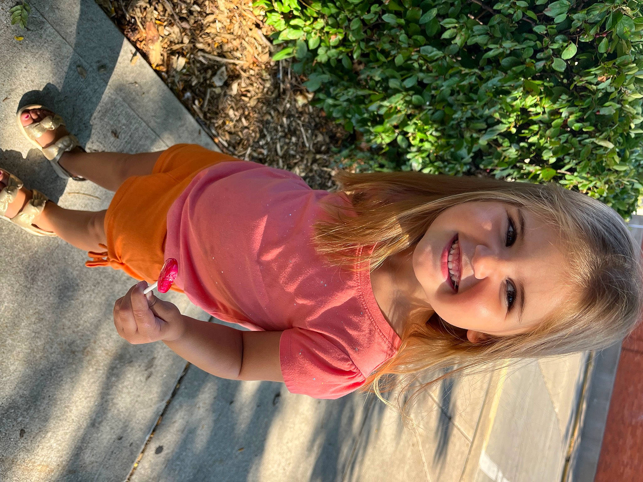 Joslyn is registered to the contest to win money with this photo: abdomen, child, fun, grass, happy, hat, human_leg, joy, landscape, leisure, people_in_nature, person, pink, plant, shadow, sitting, smile, soil, sun_hat, thigh