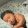 baby, sleeping, curly_hair, blanket, pillow, bed, indoor, peaceful, infant, child, rest, soft_light, cozy, toddler, skin, head, hand, face, portrait, closeup