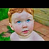 baby, bare_shoulders, blue_eyes, child, close_up, curious, curly_hair, daylight, face, garden, greenery, headshot, looking_at_camera, outdoor, patio, paving_stones, photography, portrait, red_hair, toddler