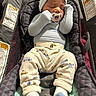 baby, infant, sleeping, pacifier, hat, bear_ears, clothing, pants, socks, baby_carrier, cushion, warning_label, indoor, cozy, cute, child, newborn, resting, soft_lighting, portrait