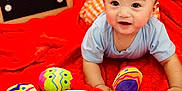 Mateo joined the competition — help win amazing prizes! baby, infant, child, toys, plush, red_blanket, colorful, smiling, face, blue_shirt, orange_shorts, wooden_board, text_board, indoor, cute, playtime, happy, soft_toys, fabric, portrait