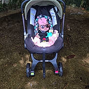 Sadie is registered to the contest to win money with this photo: baby, car_seat, sunglasses, pink_bow, infant, outdoor, stone_wall, child, toy, footwear, seatbelt, sunlight, shadow, ground, wheels, stroller, cute, fashion, accessory, relaxing