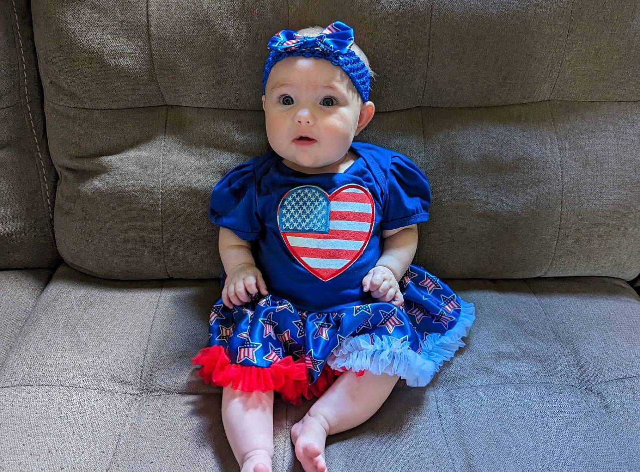 Aubree is registered to the contest to win money with this photo: baby, baby_toddler_clothing, blue, child, comfort, costume, costume_accessory, costume_hat, couch, day_dress, electric_blue, embellishment, fashion_accessory, headwear, iris, pattern, person, sitting, skin, sleeve
