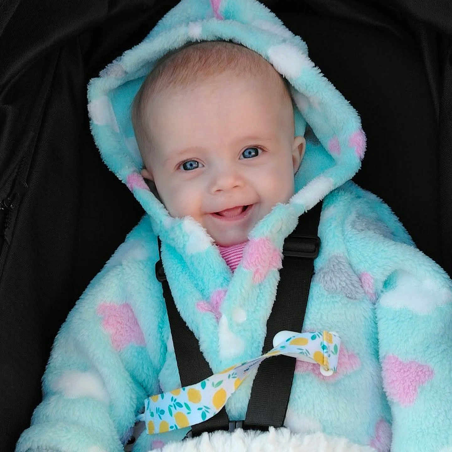 Willow joined the competition — help win amazing prizes! apparel, baby, blue, car_seat, child, closeup, cute, face, fluffy, happy, hooded_jacket, indoor, infant, pacifier_clip, person, pink, portrait, seatbelt, smile, warm_clothing