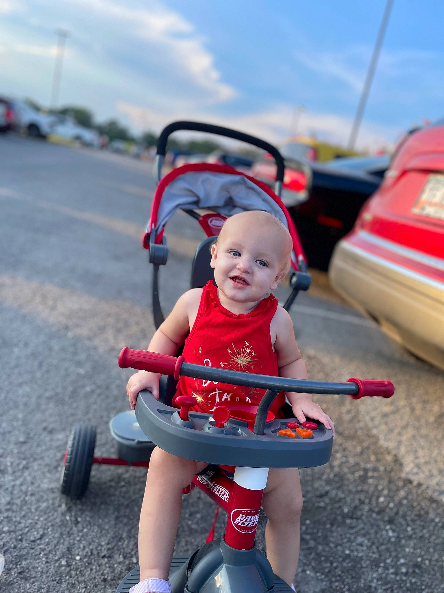 Ansleigh is registered to the contest to win money with this photo: automotive_design, automotive_tire, baby, baby_carriage, cloud, helmet, joy, leisure, mode_of_transport, motor_vehicle, outdoor_recreation, person, recreation, riding_toy, shorts, sky, smile, tire, toddler, toy