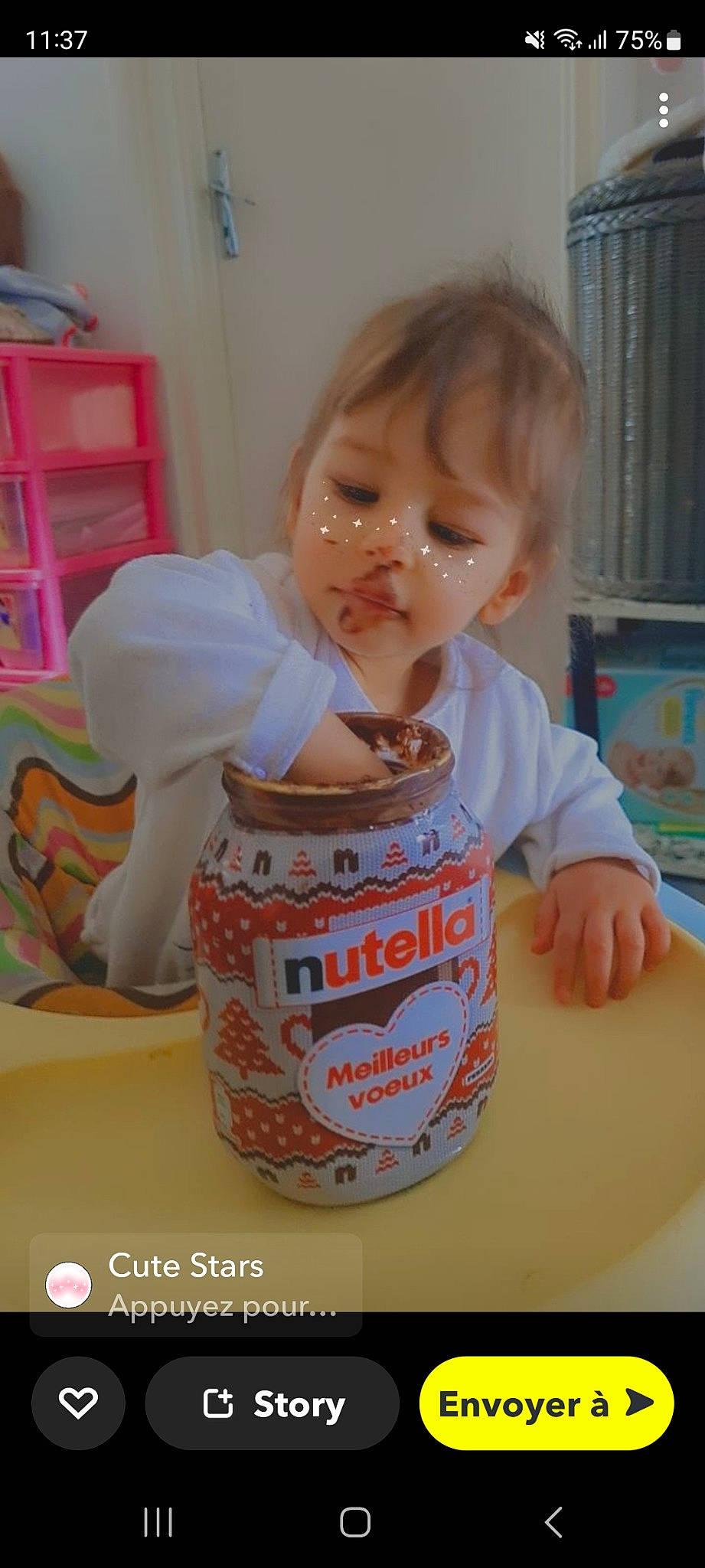 Maya participe au concours pour gagner de l'argent avec cette photo : baby, baby_toddler_clothing, bib, bookcase, cheek, child, chin, drink, drinkware, fun, happy, person, play, room, shelf, shelving, sitting, sweetness, t_shirt, toddler