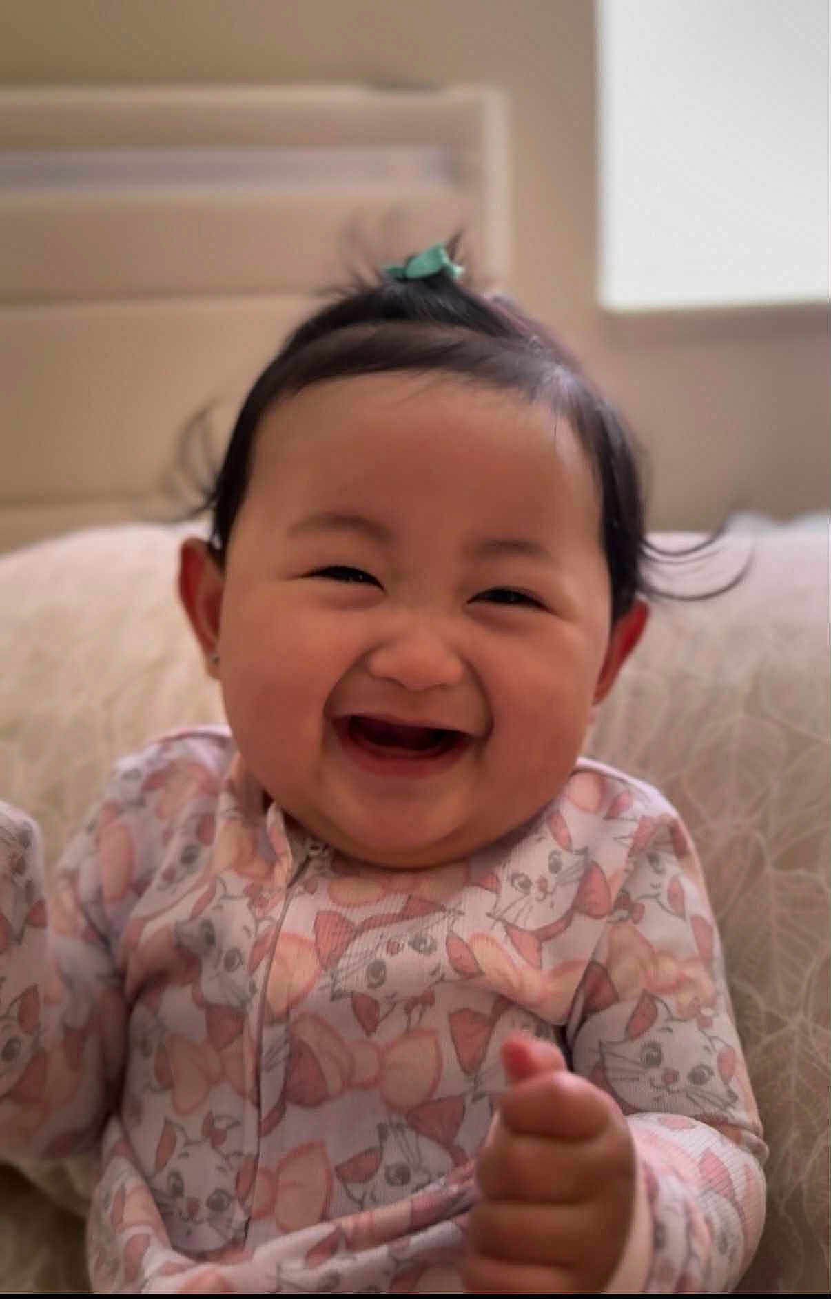 Amber joined the competition — help win amazing prizes! baby, child, smiling, happy, onesie, cute, indoor, portrait, face, hair, topknot, pillow, cozy, infant, clothing, patterned, cute_expression, young_child, sitting, joyful