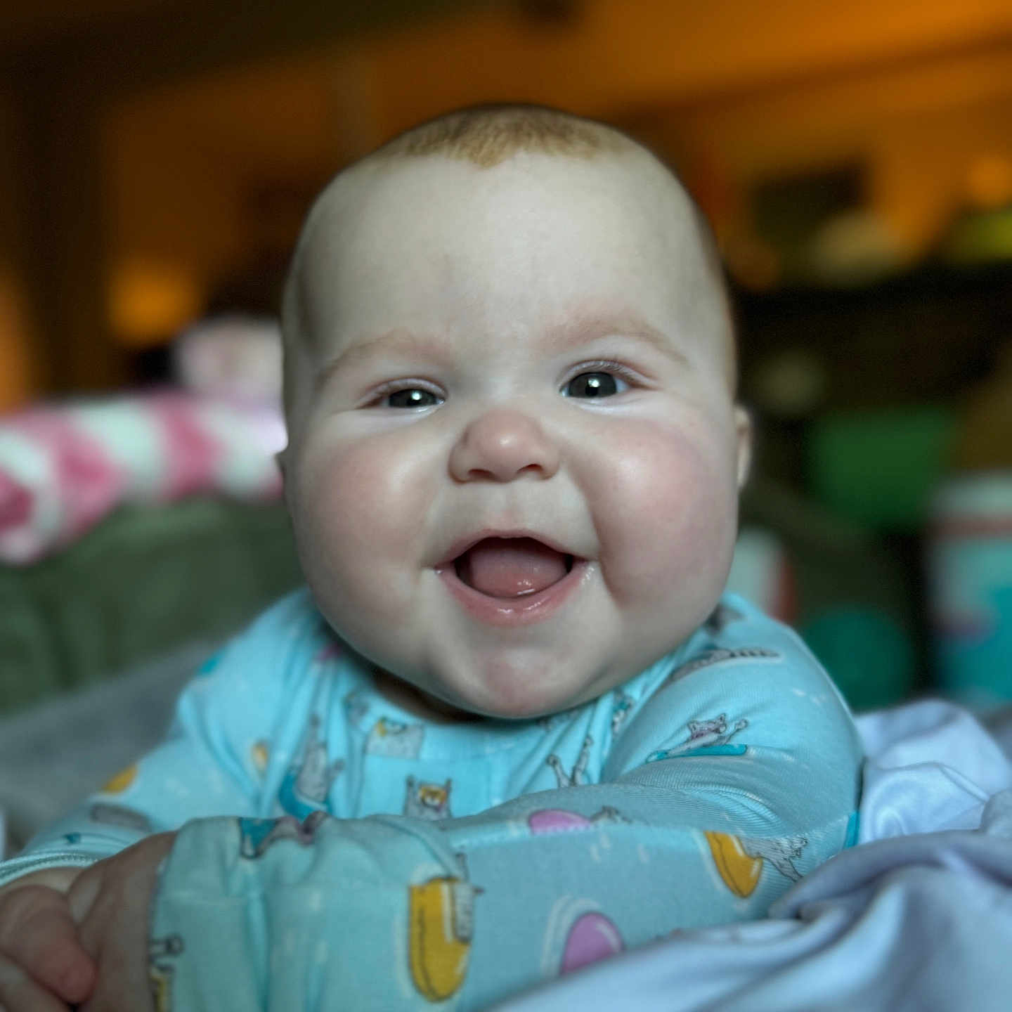 Olive is registered to the contest to win money with this photo: baby, smiling, face, child, blue_onesie, cute, happy, infant, portrait, chubby_cheeks, indoor, soft_lighting, lying_down, cute_expression, baby_clothing, closeup, young_child, playful, comfort, eyes