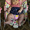 baby, infant, baby_rocker, pink, dress, stars, stripes, face, chubby_cheeks, sitting, indoor, carpet, patterned_floor, toy, colorful, heart_pattern, polka_dots, cute, child, smile