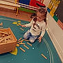 Karima participe au concours pour gagner de l'argent avec cette photo : bench, braided_hair, candid, casual_clothing, child, classroom, colors, educational_charts, floor, girl, happy, indoor, learning_environment, numbers, play_mat, playing, sparkles, toy_box, wooden_blocks, young_child