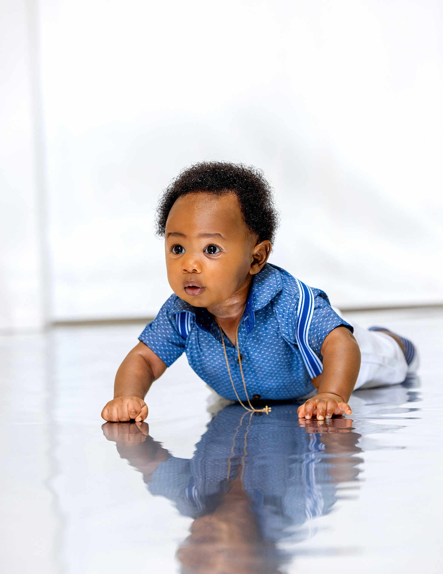 Israel joined the competition — help win amazing prizes! baby, child, crawling, blue_shirt, reflection, curly_hair, indoors, floor, suspenders, necklace, wide_eyes, cute, portrait, infant, young_child, curiosity, light_background, studio, expression, hands