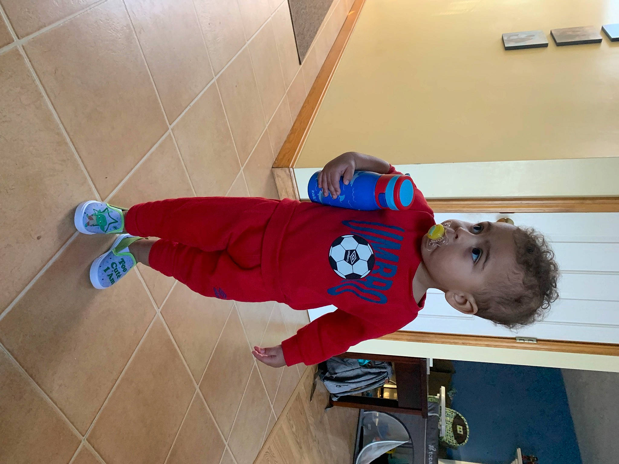 Grayson is registered to the contest to win money with this photo: carmine, child, cleanliness, elbow, electric_blue, flooring, hardwood, hat, human_leg, knee, outdoor_shoe, person, play, room, sleeve, sportswear, sweatpant, t_shirt, toddler, walking_shoe
