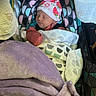 newborn, baby, sleeping, car_seat, blanket, hat, pattern, colorful, soft, cozy, infant, child, wrapped, cute, peaceful, indoors, fabric, resting, wearing, portrait
