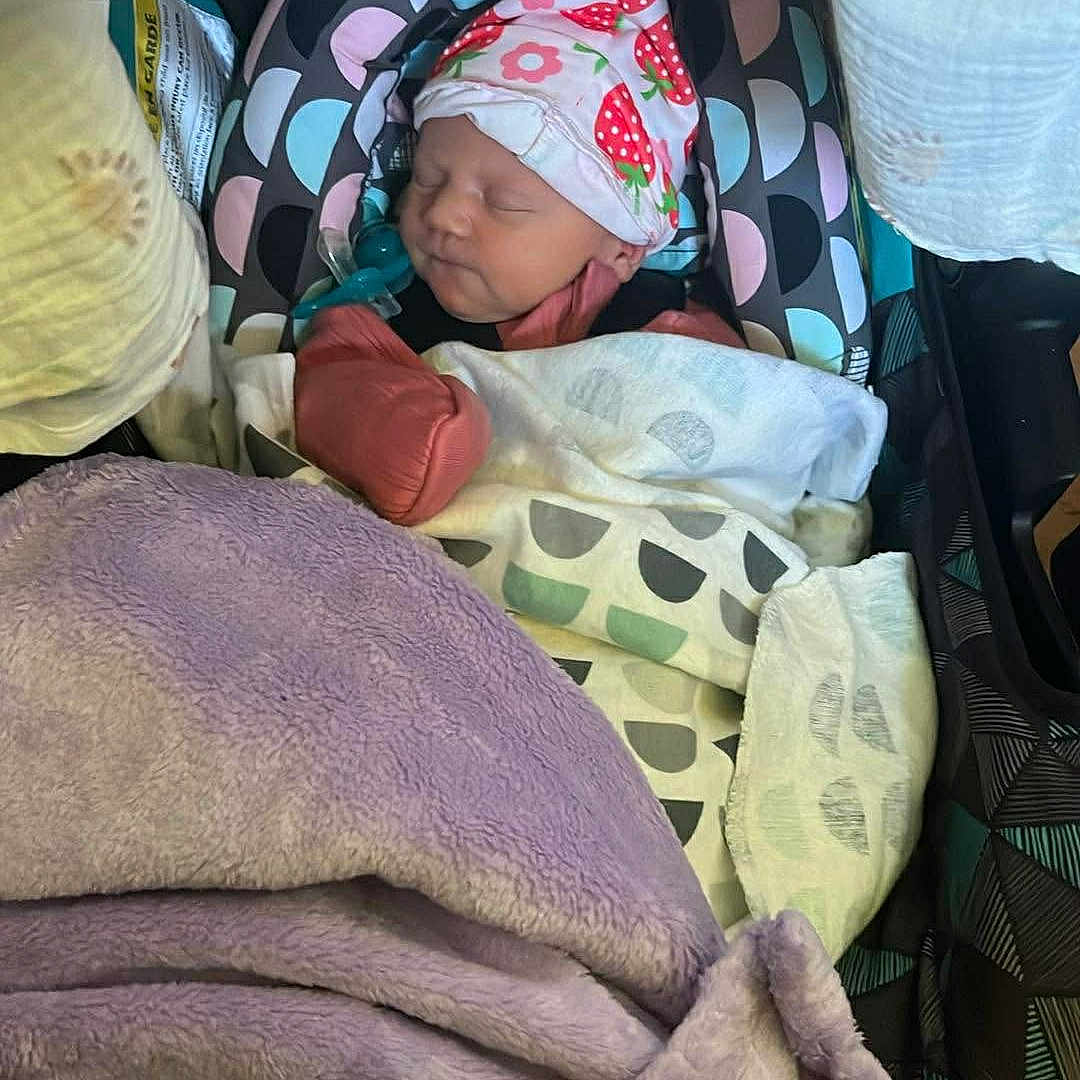 Briella joined the competition — help win amazing prizes! newborn, baby, sleeping, car_seat, blanket, hat, pattern, colorful, soft, cozy, infant, child, wrapped, cute, peaceful, indoors, fabric, resting, wearing, portrait