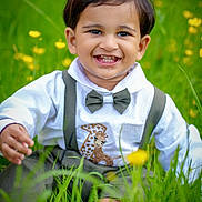 Noah joined the competition — help win amazing prizes! toddler, child, smiling, grass, outdoor, wildflowers, greenery, cute, happy, portrait, bow_tie, suspenders, white_shirt, nature, baby, young_child, sitting, daylight, casual_clothing, closeup