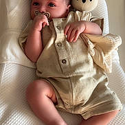 Nils participe au concours pour gagner de l'argent avec cette photo : baby, infant, pacifier, stuffed_animal, romper, cushion, white, beige, sleeping_bed, hand, foot, face, child, indoor, soft_toy, texture, comfort, cute, relaxing, newborn