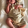 baby, infant, pacifier, stuffed_animal, romper, cushion, white, beige, sleeping_bed, hand, foot, face, child, indoor, soft_toy, texture, comfort, cute, relaxing, newborn