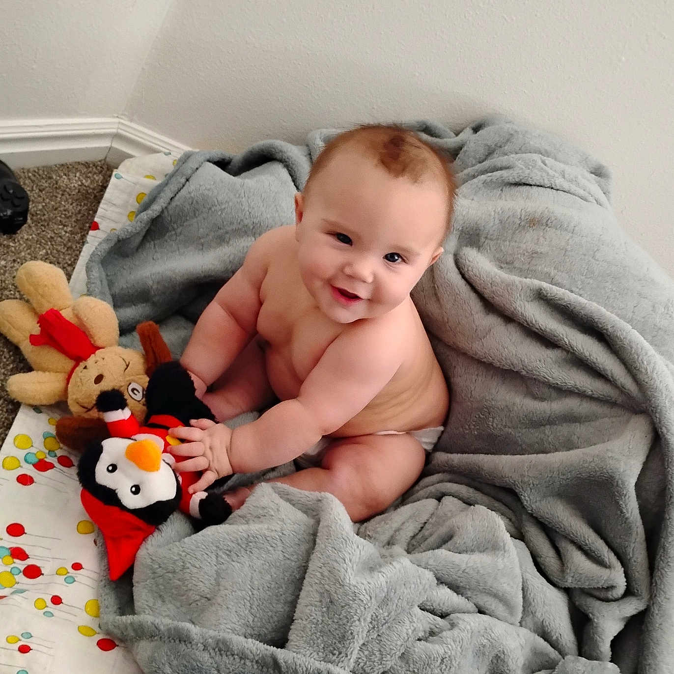 Christopher James joined the competition — help win amazing prizes! baby, blanket, carpet, child, chubby, cozy, cute, diaper, face, happy, indoors, penguin, person, plush_toy, quilt, reindeer, sitting, smiling, soft, toy