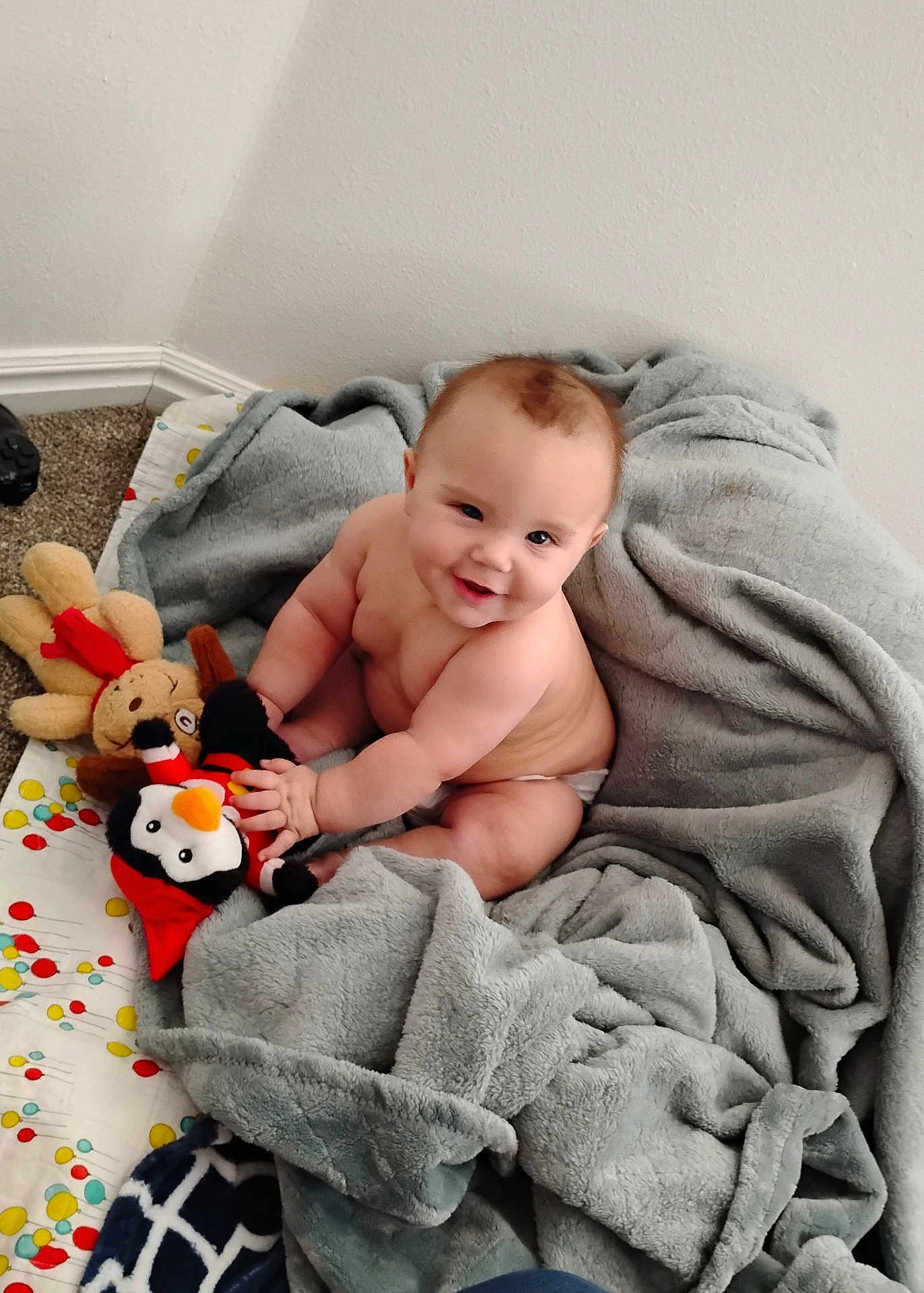 Christopher James joined the competition — help win amazing prizes! baby, blanket, carpet, child, chubby, cozy, cute, diaper, face, happy, indoors, penguin, person, plush_toy, quilt, reindeer, sitting, smiling, soft, toy