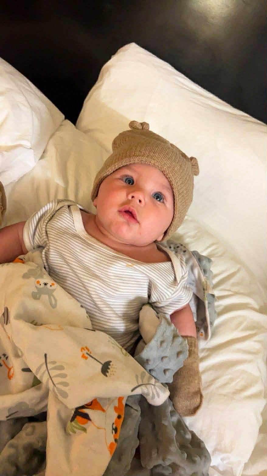 Christopher James joined the competition — help win amazing prizes! baby, blanket, bed, hat, infant, clothing, cute, face, headwear, lying_down, mittens, person, portrait, resting, soft, striped_shirt, warm, white_bed, blue_eyes, cozy