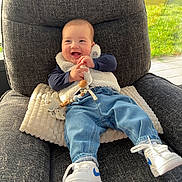 Hugo participe au concours pour gagner de l'argent avec cette photo : armchair, baby, casual, child, clothing, cushion, footwear, happy, indoor, jeans, pacifier, person, relaxing, smiling, sneakers, sunlight, toy, vest, window, wooden_beads