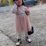 Anehyra participe au concours pour gagner de l'argent avec cette photo : child, girl, pink_dress, tulle_skirt, floral_boots, handbag, phone, outdoor, concrete, car, wooden_door, curious_expression, long_hair, playful, sidewalk, trees, casual, daylight, portrait, standing