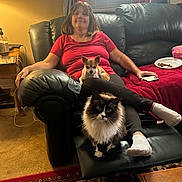 Kitie Marie joined the competition — help win amazing prizes! woman, dog, cat, couch, living_room, carpet, table, lamp, air_conditioner, curtains, red_shirt, black_pants, socks, pet, relaxing, indoor, furniture, portrait, home, cozy