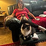 woman, dog, cat, couch, living_room, carpet, table, lamp, air_conditioner, curtains, red_shirt, black_pants, socks, pet, relaxing, indoor, furniture, portrait, home, cozy